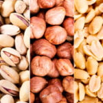 A close-up view of various nuts arranged in vertical sections, from left to right: hazelnuts, walnuts, pistachios, hazelnuts again, peanuts, peanuts in shells, and a mixed assortment of nuts including almonds, hazelnuts, and others.