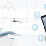 Modern dental clinic with a dental chair on the left and a close-up of a hand interacting with a tablet showing dental icons on the right, representing technology integration in dental practices.